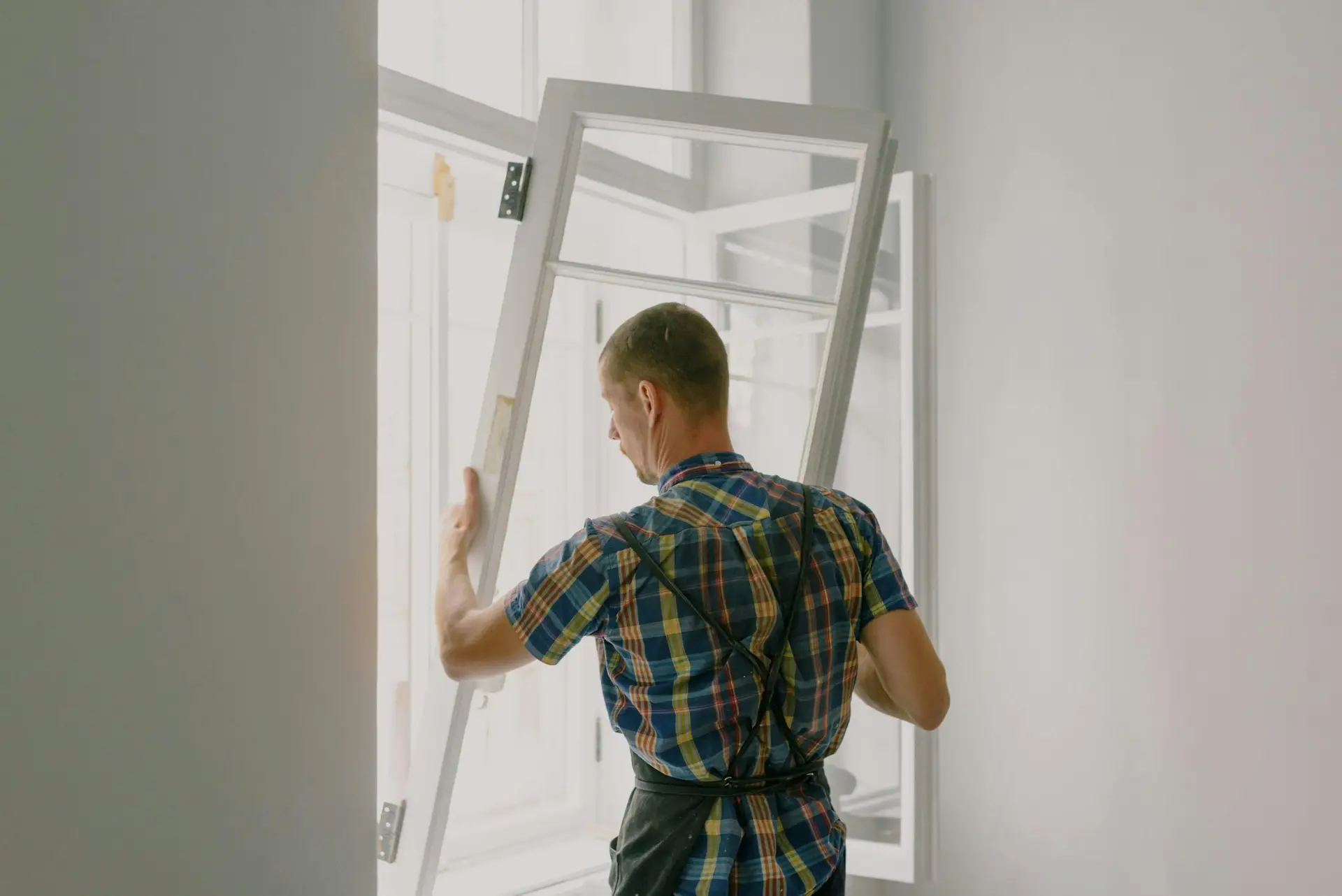 A professional installer fitting a modern window in a well-lit home interior.