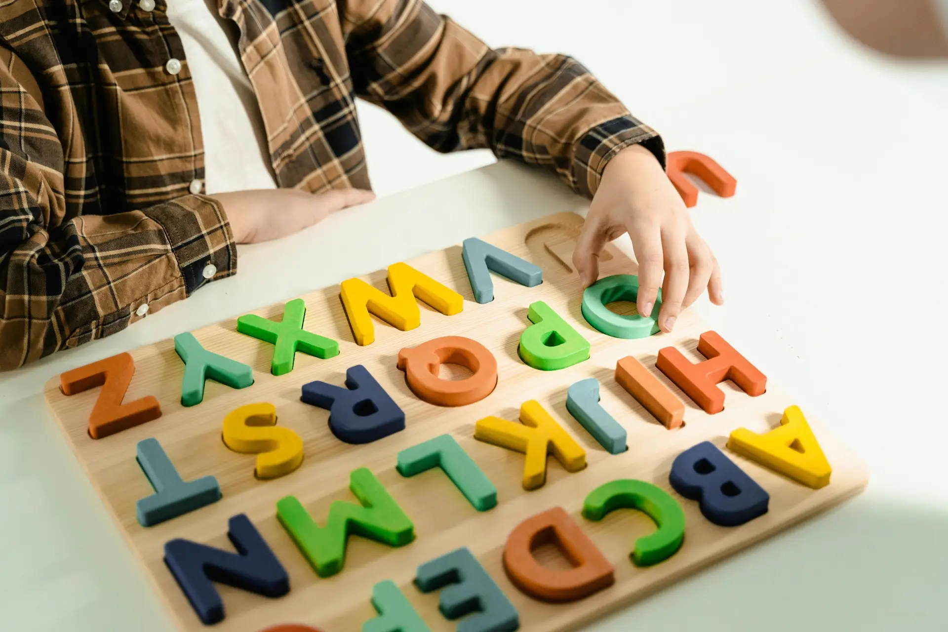 A child interacts with bright wooden alphabet letters, engaging in educational play.